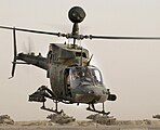 Un OH-58 Kiowa mostrant la seva mira montada en el màstil, un míssil antitancs i un contenidor de coets.