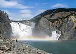 Large but relatively low waterfall through rocks.