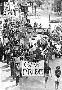 Marchers going down Nicollet Mall holding signs. In front is a big banner saying GAY PRIDE