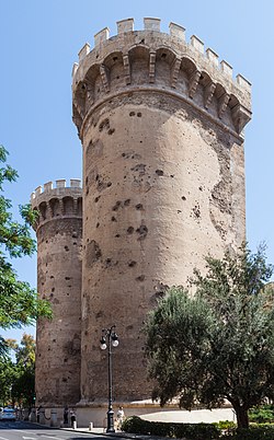 two stone towers on a city street with green trees and a blue sky