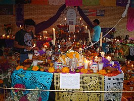 An elaborate Ofrenda seen with decorative papel picados