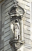 Statuette en pierre d'une femme en robe, à l'angle d'un immeuble