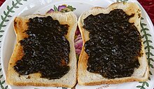 Auf einem Teller liegen zwei Scheiben Toastbrot, die mit einer Art dunkelbraunen Marmelade bestrichen sind.
