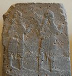 לוחמים מחזיקים מגן עגול על גבי אורתוסטאט מבזלת מהמאה ה-8 לפנה"ס
