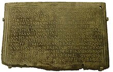 Spatynowana brązowa tabliczka zapisana horyzontalnie 15 liniami tekstu łacińskiego, wokół tekstu prosta ramka w postaci trzech wypukłych linii, w prawym górnym rogu wywiercony otwór.