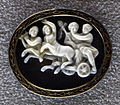 Petite sculpture ovale blanche sur fond noir avec 4 personnages.
