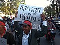 An opposition protester marches, holding up a sign that says "Re-election".