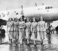 A black-and-white photograph of a Martin 2-0-2 aircraft with six cabin crew standing in front of the aircraft