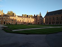 View over Liddon Quad covered in grass from the Chapel looking towards the Porter's Lodge. The building is the famous red brick.