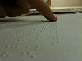 Meriv bi alîkariya tiliya xwe nivîsa Braille dixwîne.