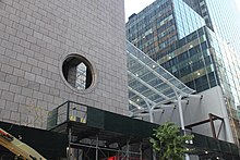 The northern facade of the building, looking west from 56th Street. There is a pink granite facade at the left and a glass-roofed atrium at the center.