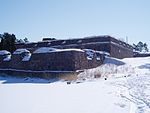 I förgrunden ser man fästningens huvudport med tenaljens skyddande hörn och i bakgrunden ser man bastion Nordenskiöld.