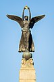 Winged figure holding a golden crown at the top of the obelisk