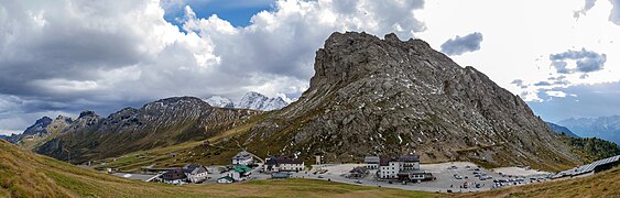 Panorama von Passhöhe und Abfahrt in Richtung Buchenstein, im Vordergrund der Sasso Beccé, links der Padonkamm, dahinter die schneebedeckte Marmolata