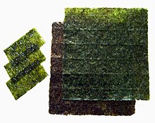 Auf weißem Hintergrund liegen mehrere Blätter aus grünem oder bräunlich-grünem Pflanzenmaterial, deren Aussehen an durchscheinendes handgeschöpftes Papier erinnert.