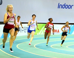 Sprinters leaning into a turn on a banked indoor track