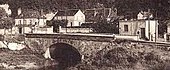 Extrait d'une ancienne photographie en noir et blanc représentant un ouvrage d'art franchissant un fleuve et reliant deux communes.