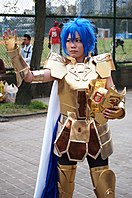 Homme aux cheveux bleus portant une armure dorée et un casque orné.