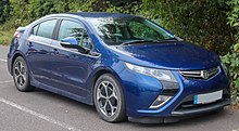 Front 3/4 view of a dark blue automobile with trees in the background and a UK licence plate