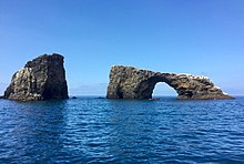 View of Arch Rock with calm ocean in front