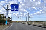 左岸側の橋梁手前の案内標識。道路が大きくカーブして橋梁に至ることが示されている（2020年3月）
