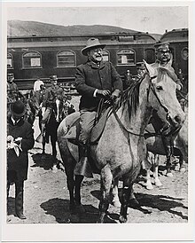 Roosevelt sits on horseback sporting a large grin.