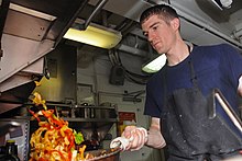 Sautéed vegetables being tossed in a sauté pan