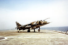 A Harrier on the deck of a small aircraft carrier, with its nose wheel off the deck