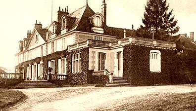 Photographie en noir et blanc de la façade d'un château et de son domaine.