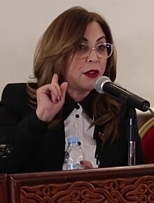 Asmaa Rhlalou first female Mayor of Rabat wearing glasses and speaking into a microphone.