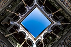 Sunlight over central courtyard shot from directly below and surrounded by patterned tiles and galleries on the floors beneath it