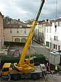 Grue autoportée mettant en place un conteneur enterré à ordures ménagères.