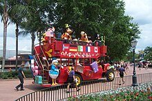 A red turn-of-the-20th-century-style double-decker bus with costumed characters