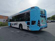 Photo de l'arrière d'un midibus de couleur blanc et turquoise.