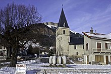 Église dans un village sous la neige avec une montagne en arrière-plan.