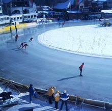 A view of a ski jump hill with crowds surrounding the landing area