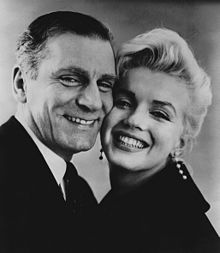 Close-up of smiling Monroe and Laurence Olivier, cheek-to-cheek. She is wearing long diamond earrings.