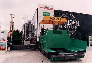 A road paver. The rollers at the front push the truck along while unloading. The slat conveyor in the middle drags the asphalt to the back.