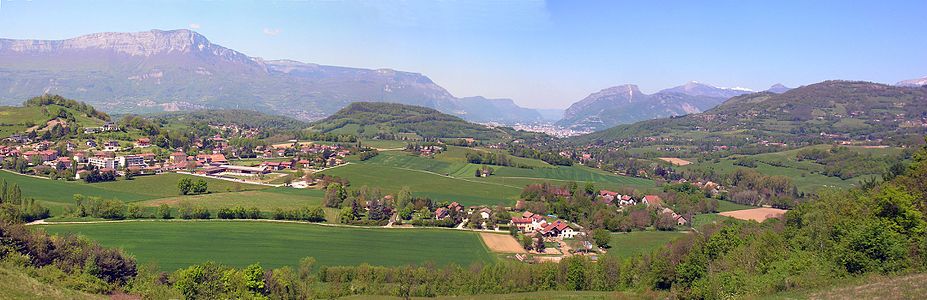 Cliché panoramique visualisant une étendue vallonnée et montagneuse en arrière-plan. Quatre hameaux l'occupent.