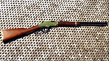 Image of a Henry Golden Boy rifle laying on a wooden floor.