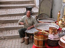 Man making large copper vat with stairs in background