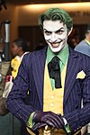 Photo en buste d'un homme déguisé en Joker, avec un sourire machiavélique.