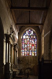 Photographie montrant un bras de transept d'église, couvert d'un lambris et éclairé par un vitrail