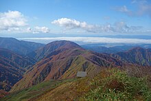 避難小屋と雲海広がる新庄盆地(左奥は月山)