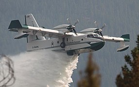 vue d'un canadair blanc et bleu en train de larguer de l'eau.