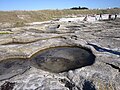 Trous circulaires sur l'estran rocheux granitique à l'ouest de Guilvinec, qui correspondent à l'extraction de socles en rond pour la construction de calvaires ou croix.