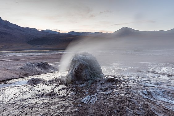 The vent is a small cone surrounded by steam in an unvegetated landscape