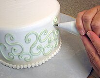 Прикрашання торта – масляний крем створює візерунки на боках цього торта за допомогою кондитерського мішка