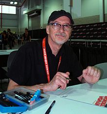 Nowlan seated at a table, with paper and drawing instruments