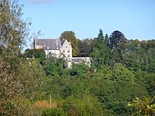 Vue d'un petit château émergeant de la végétation, au flanc d'un coteau.